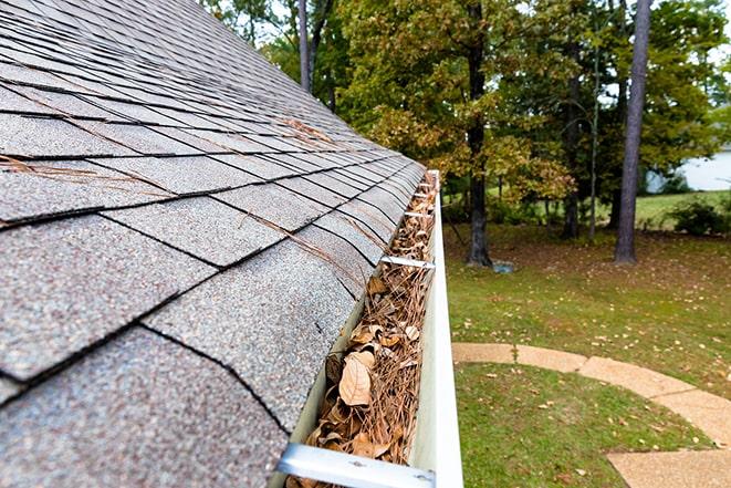 clearing clogged gutters to prevent water damage